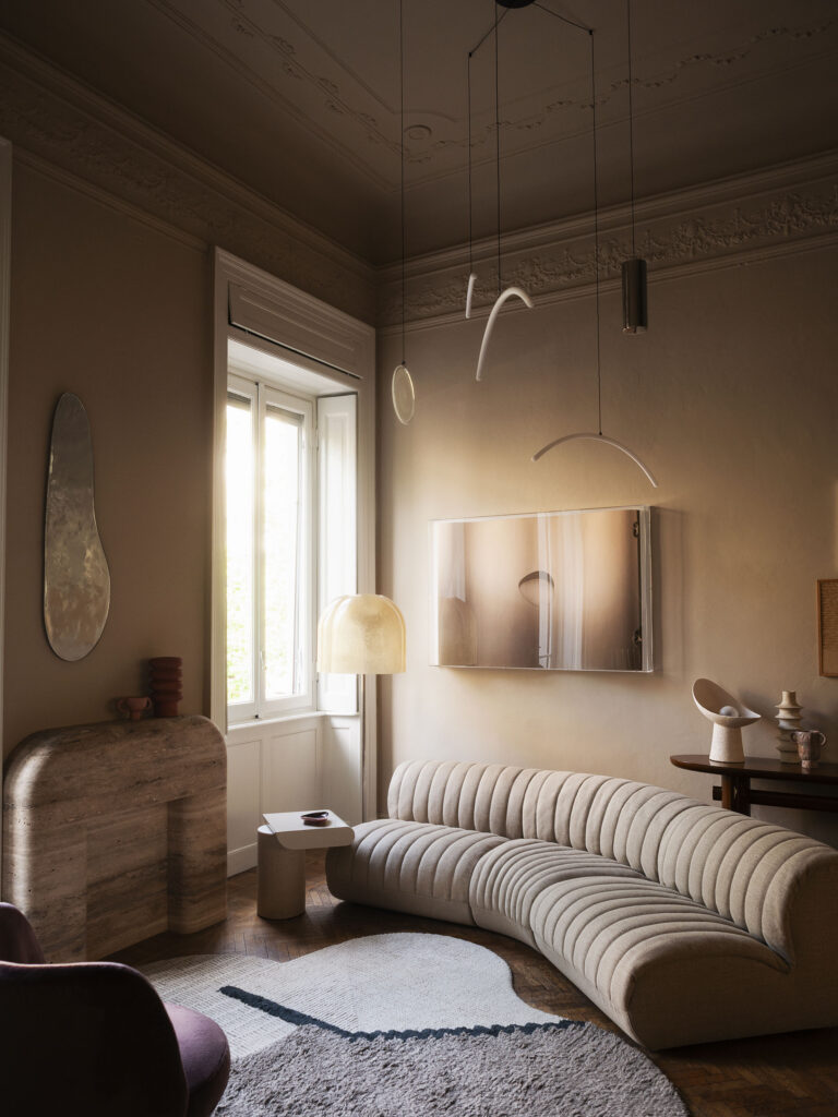 Salone con stucchi d'epoca, pavimento a spina di pesce e divano curvo — The Intimacy, Viale Abruzzi Milano