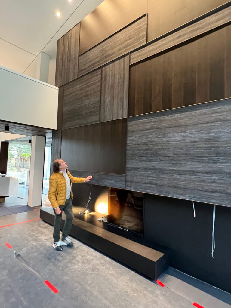 Rivestimento murale in rovere su misura e camino personalizzato durante la fase di installazione